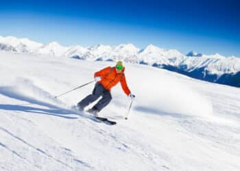 Young skier in mask sliding fast while skiing view during sunny winter day on Krasnaya polyana ski resort and Caucasus mountains in Sochi, Russia