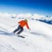 Skier in mask slides fast while skiing from slope